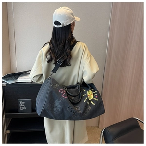 Black canvas travel bag with colorful graffiti print shown worn by a model in a room