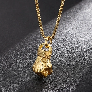 Macro close-up showing the intricate texture of the golden metal fist pendant necklace