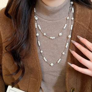 Close-up of double-layered long pearl necklace with silver metal links on a model