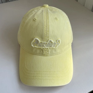 Close-up of washed yellow cotton baseball cap with embroidered patch and vintage details