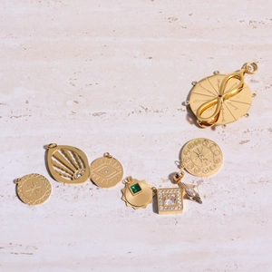 Gold plated tarot and zodiac pendants with zircon stones on a white marble background