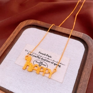 Macro detail of a 24K gold-plated necklace featuring a HAPPY pendant and giraffe silhouette