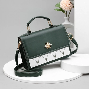 Vintage dark green top-handle bag with white panel and gold bee buckle on a pedestal