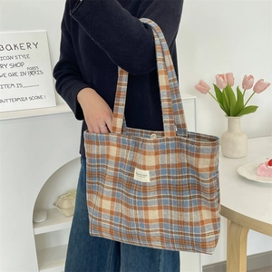 Detail of plaid wool tote bag showing thick orange and blue woven fabric texture