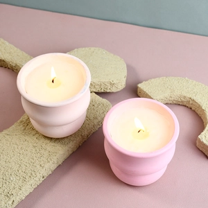 Macro di due tazze per candele profumate rosa pastello su uno sfondo opaco