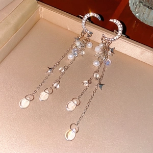 Star and moon fringe earrings with diamonds and pearls displayed in a luxury jewelry box