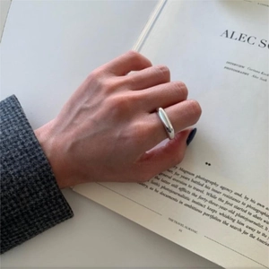 Close-up of minimalist irregular silver ring worn on index finger over a magazine