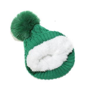 Détail du bonnet en tricot vert foncé avec doublure en peau de mouton blanche et pompon