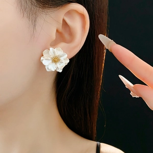 Close-up of white flower stud earrings with gold stamen on a person's ear