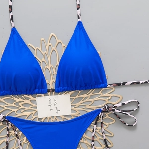 Flat lay of royal blue bikini with leopard print ties on a gold decorative mat