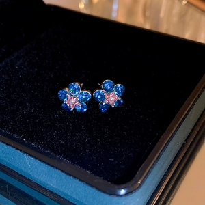 Macro detail of blue flower stud earrings with crystals in a dark jewelry box