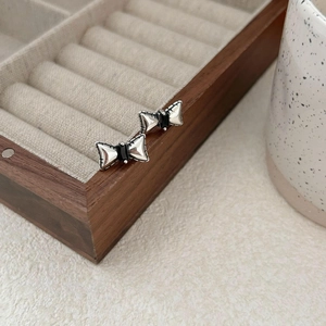Detailed view of 925 silver bow earrings with black zircon on a wooden box