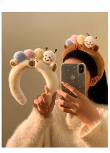 Close-up of soft plush caterpillar headbands in beige and brown colors with colorful pom-poms