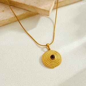 Gros plan d'un collier pendentif oeil de tigre doré vintage sur socle en pierre