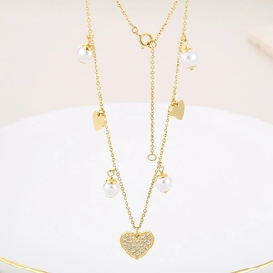Detail of gold-plated necklace with white faux pearls and a sparkling heart pendant