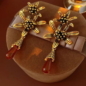 Close-up of vintage gold flower earrings with amber water drop pendants on a ribbon box