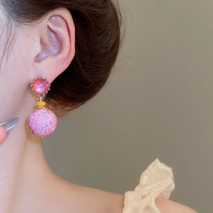 Detailed close-up of pink beaded resin drop earrings worn by model with gold hardware