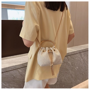 Close-up of sparkling rhinestone bucket bag with golden ring handle and tassel detail