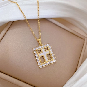 Close-up of gold titanium cross pendant with white inlay and shimmering crystal detail