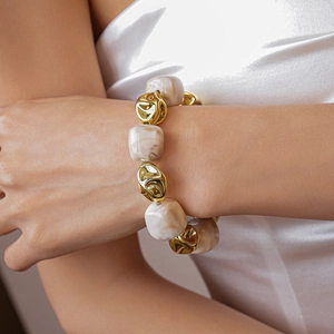 Detail of irregular acrylic beads and molten gold metal spheres on a stylish necklace