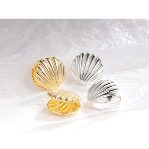 Detail of minimalist gold and silver shell-shaped earrings showing open and closed designs