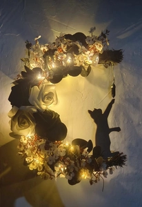 Detail of crescent moon cat wreath with black and white roses and glowing LED lights