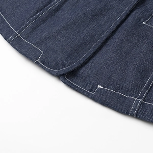 Détail rapproché des surpiqûres blanches contrastées sur le tissu denim bleu foncé