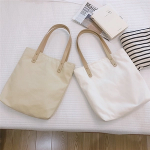 Detail of canvas tote bag showing thick fabric texture and faux leather handles with rivets