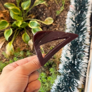 Detail of a dark brown triangular hair claw clip with a glossy finish for thick hair
