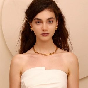 Detail view of a model wearing a gold starfish earring and a minimalist curved choker set