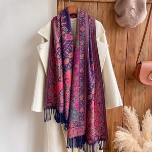 Close-up of bohemian paisley floral shawl with fringe on a white wool coat decor
