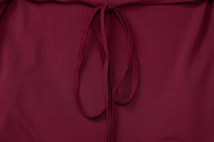 Detail of burgundy dress showing refined tie-up knot design and premium elastic fabric texture