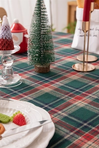 Close-up of red and green plaid Christmas tablecloth with festive holiday decorations