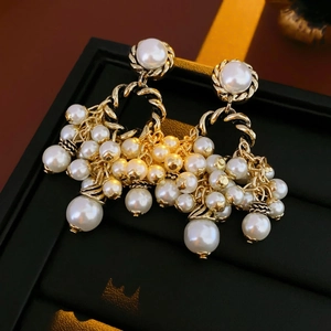 Detailed close-up of vintage golden pearl tassel earrings on a dark display stand