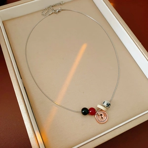 Macro shot of silver necklace with multi-colored beads and rose gold engraved pendant