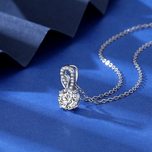 Macro detail of 2-carat zircon pendant necklace with curved diamond accents on silk