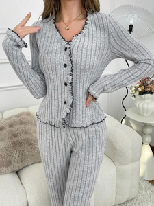 Detail of light grey knit pajama set with black wavy trim and buttoned V-neck top