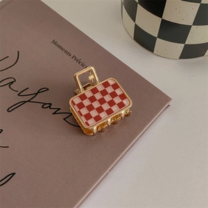 Detail of red and pink checkered handbag shaped hair claw clip on a book cover