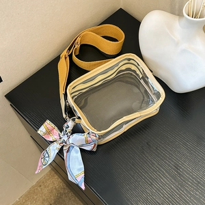 Detailed view of clear PVC crossbody bag featuring a bold yellow strap and decorative scarf