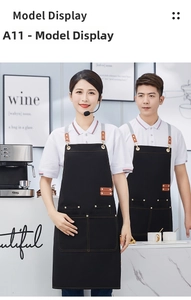 Close-up of black canvas apron with brown leather straps and metal hardware detail