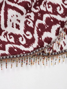 Detail von rot-weißem Ikat-Muster mit bunten Perlenfransen und Quasten-Abschluss