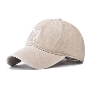 Close-up of vintage heart embroidery and washed canvas texture on a baseball cap