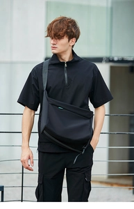 Borsa a tracolla in nylon nero impermeabile indossata da un modello in stile urbano