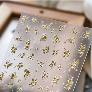 Macro shot of 3D gold embossed nail stickers with intricate leaf and butterfly patterns