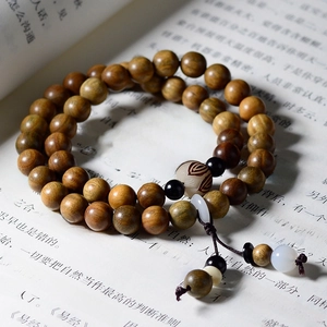 Detailed view of Verawood double-loop prayer beads with lotus pendant on book