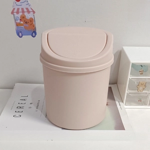 Cute pink desktop mini trash can with press-top lid on a magazine for office storage
