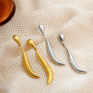 Detailed view of elegant gold and silver long curved teardrop earrings on beige fabric