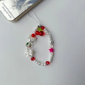 Detailed view of cherry bead charm with pearls and bow on a white lanyard for bags