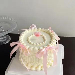 Gâteau style ballet à nœud rose avec bougie cœur sur base crème pour anniversaire