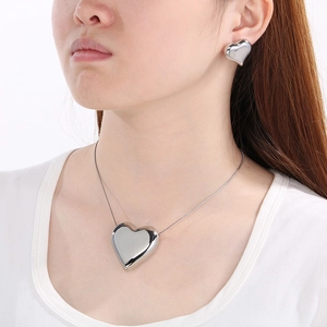 Détail d'un ensemble collier et boucles d'oreilles cœur en argent porté par un mannequin